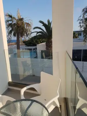 a glass table and white chairs on a balcony at Christopher's Sandy Beach Suites in Ayia Napa