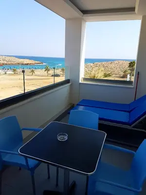 a table and chairs in a room with a view of the beach at Christopher's Sandy Beach Suites in Ayia Napa