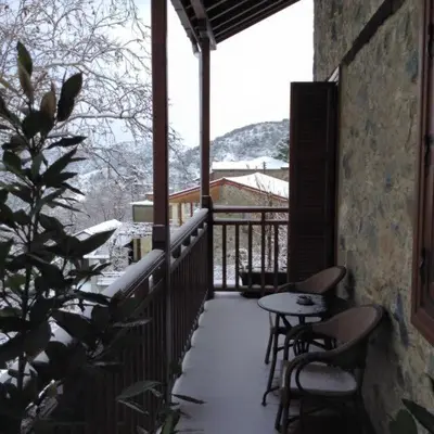 a balcony with a table and chairs in the snow at Aristotelio Boutique Hotel in Pedoulas