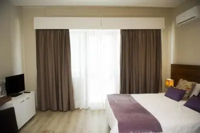 a bedroom with a bed and a large window at Manolia City Residences in Nicosia
