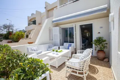 a balcony with white chairs and a table at Protaras Central Sunrise in Protaras