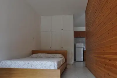 a bedroom with a bed and white cabinets and a refrigerator at Royal Sunset Studios & Apartments in Limassol