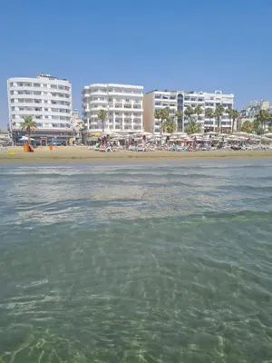 a view of a beach with buildings in the background at Alex Beach Apartment 31 in Larnaka