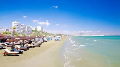 a beach with chairs and umbrellas and the ocean at Alex Beach Apartment 31 in Larnaka