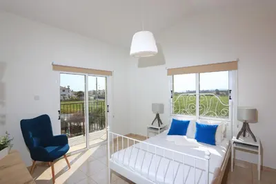 a bedroom with a bed and a blue chair at SeaBreeze Villas by TrulyCyprus in Ayia Napa