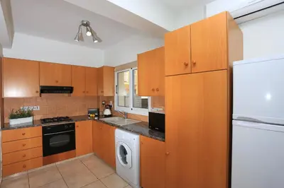 a kitchen with wooden cabinets and a washer and dryer at SeaBreeze Villas by TrulyCyprus in Ayia Napa