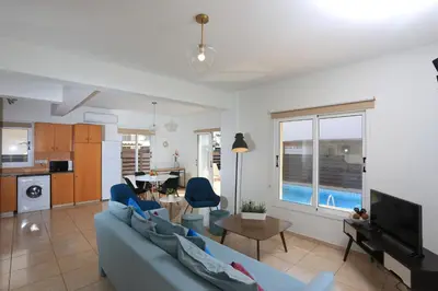 a living room with a blue couch and a table at SeaBreeze Villas by TrulyCyprus in Ayia Napa