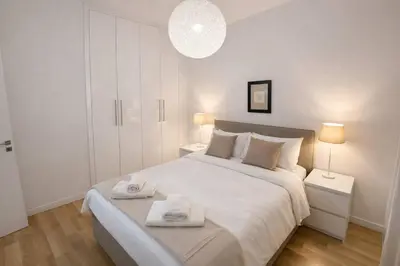 a white bedroom with a large bed with towels on it at SeaBreeze City Center Flats by TrulyCyprus in Limassol