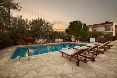 a swimming pool with chaises and chairs next to at Meleni Cottage Houses in Parekklisha