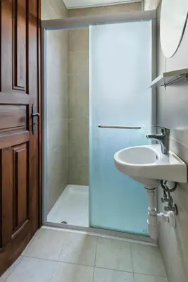 a bathroom with a glass shower door and a sink at Meleni Cottage Houses in Parekklisha