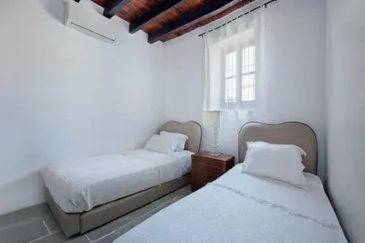 two beds in a white room with a window at Meleni Cottage Houses in Parekklisha
