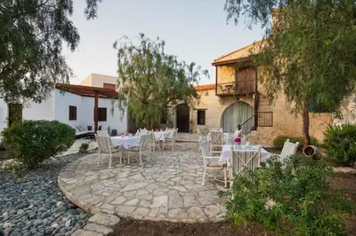 a patio with tables and chairs in front of a building at Meleni Cottage Houses in Parekklisha