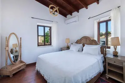 a white bedroom with a large bed and a mirror at Meleni Cottage Houses in Parekklisha