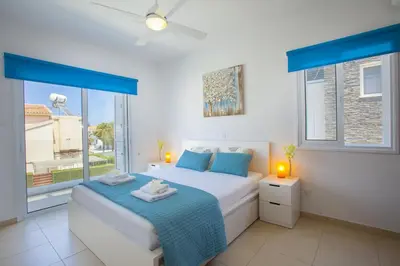 a bedroom with two beds and a large window at Protaras Villa Anemoni 6 in Protaras