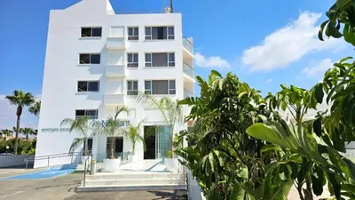 a white building with trees in front of it at NissiLant hotel & suites in Ayia Napa