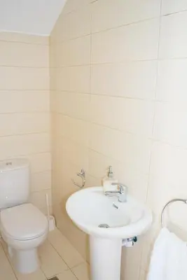 a white bathroom with a toilet and a sink at T&E Villa in Larnaka
