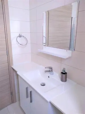 a white bathroom with a sink and a mirror at T&E Villa in Larnaka