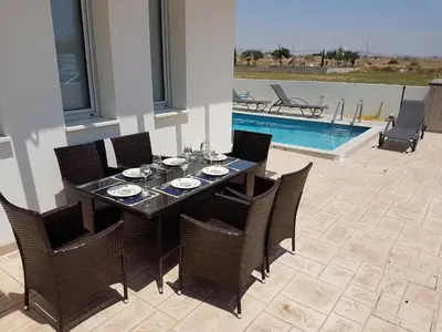 a dining room table and chairs and a swimming pool at T&E Villa in Larnaka