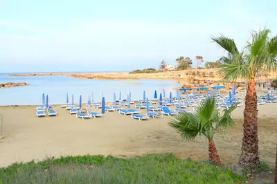 a group of chairs and umbrellas on a beach at Green Bay Villa in Protaras