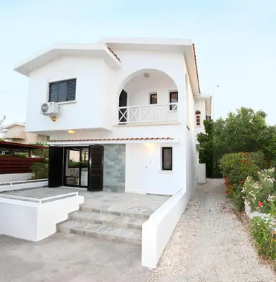 a white house with stairs in front of it at Green Bay Villa in Protaras