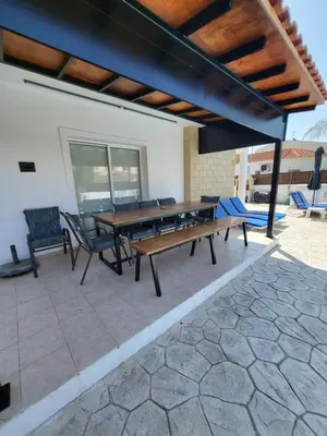 a patio with a wooden table and chairs at Villa Gracia in Ayia Napa