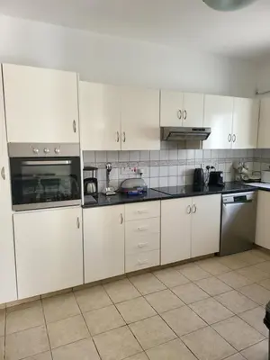 a white kitchen with white cabinets and appliances at Villa Gracia in Ayia Napa