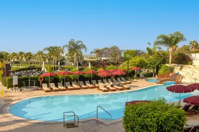 a swimming pool with chairs and umbrellas at St Raphael Resort in Limassol