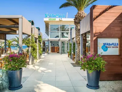 a shopping mall with palm trees and a building at St Raphael Resort in Limassol