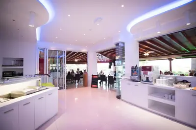 a kitchen with white counters and people in the background at Loutsiana Deluxe Apts in Ayia Napa