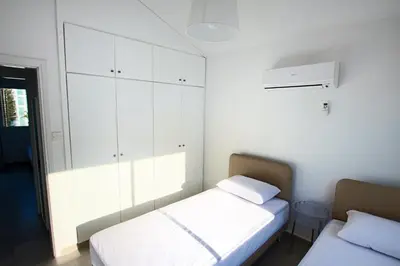 a bedroom with two beds and white cabinets at Fig Tree Bay Villa 2 in Protaras