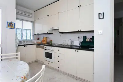 a kitchen with white cabinets and a table at Despoina Town House in Limassol