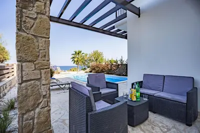 a patio with chairs and a table next to a swimming pool at Greko Mare Front Line in Protaras