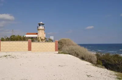 a lighthouse sitting on top of a hill next to the ocean at Sunset Garden Villa in Pervolia