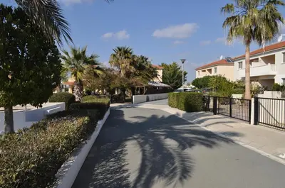 a driveway with palm trees and a fence at Sunset Garden Villa in Pervolia
