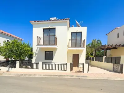 a white apartment building with a blue sky in the background at Villa Chrysa in Protaras