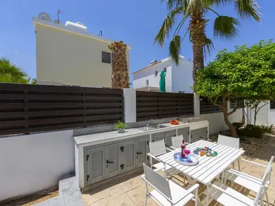 a patio with a table and chairs and a sink at Passion Villa in Protaras