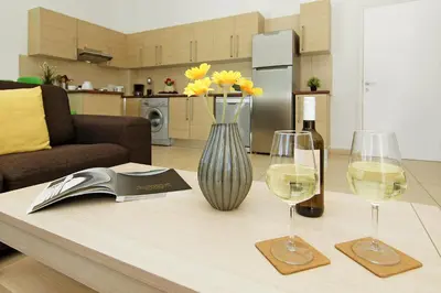 a table with two glasses of wine and a vase of flowers at Calypso - Coralli Beachfront Apartment in Protaras