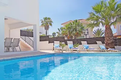 a swimming pool with lounge chairs and palm trees at Villa Anette in Protaras