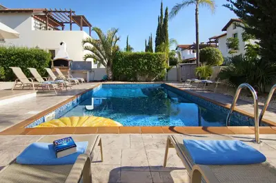 a swimming pool with chairs and a house at Villa Ingrid in Ayia Napa