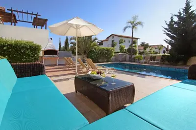 a patio with a table and an umbrella next to a pool at Villa Ingrid in Ayia Napa