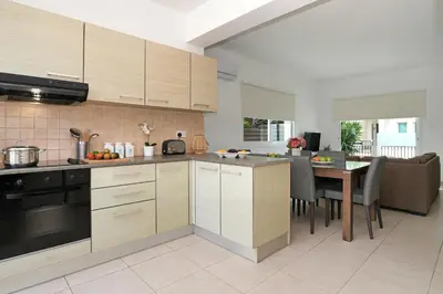 a kitchen with wooden cabinets and a table with chairs at Villa Summer in Protaras