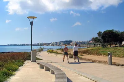 two people walking on a sidewalk next to the water at Villa Summer in Protaras