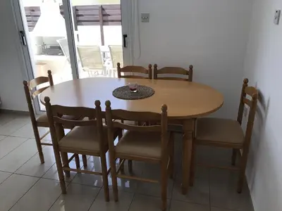 a wooden table and chairs with a table and a window at Villa Nissi Beach 28 in Ayia Napa