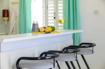 a white counter with three bar stools and a glass of wine at Protaras Holiday Suite Annie in Protaras