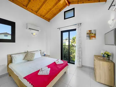 a bedroom with a large bed with a red blanket at Kymma Villa #16 in Ayia Napa