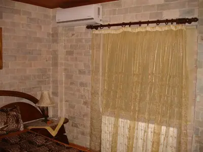 a bedroom with a curtain and a bed and a fan at The Love Holiday House in Tris Elies