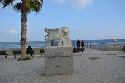 a statue of a lion standing next to the beach at P L PANAGIOTIS Apartment in Larnaka