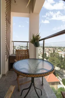 a table and a chair on a balcony with a view at Vas' Penthouse in Nicosia