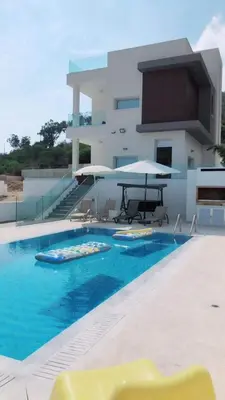 a swimming pool with chairs and umbrellas next to a building at Villa Spathele in Paralimni