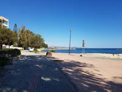 a brick road next to a beach with the ocean at Galatex Beach Apartment in Limassol